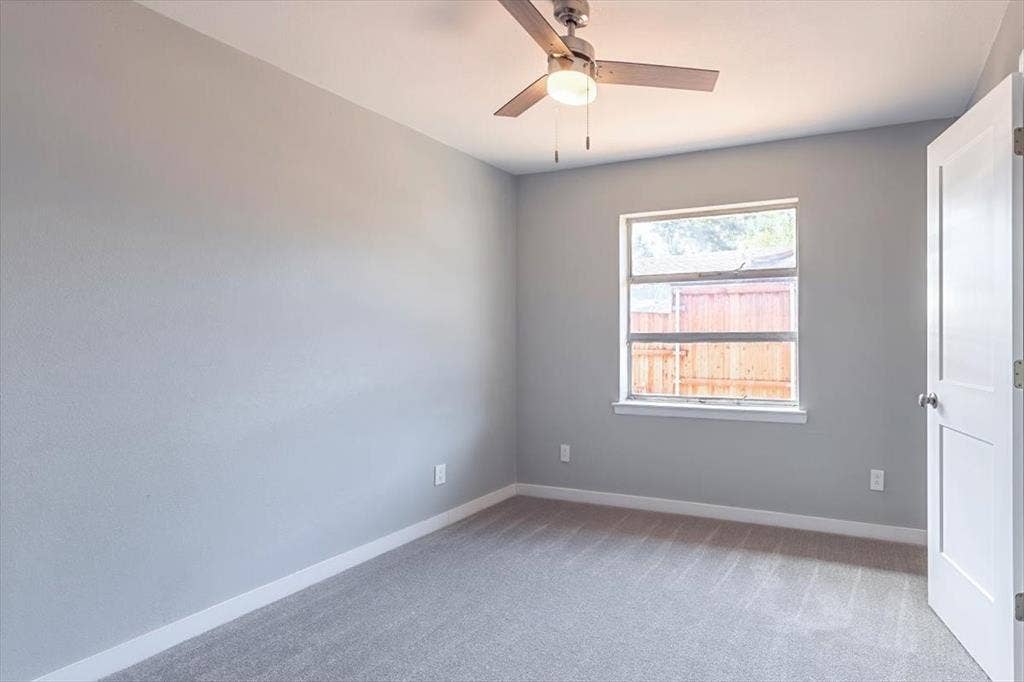 12326 Dandridge Drive, Dallas, TX 75243 Ceiling fan with light fixture, light gray wall paint, window with white trim, and gray carpet