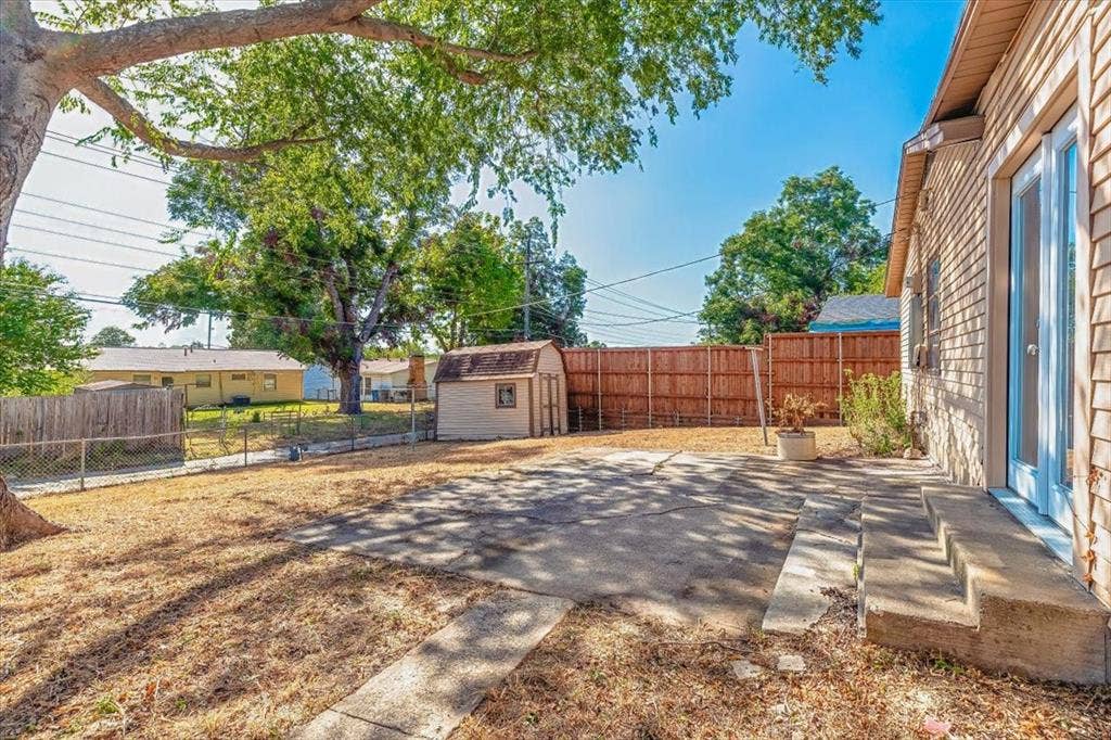 12326 Dandridge Drive, Dallas, TX 75243 Expansive outdoor space featuring a paved patio, a storage shed, and a privacy fence