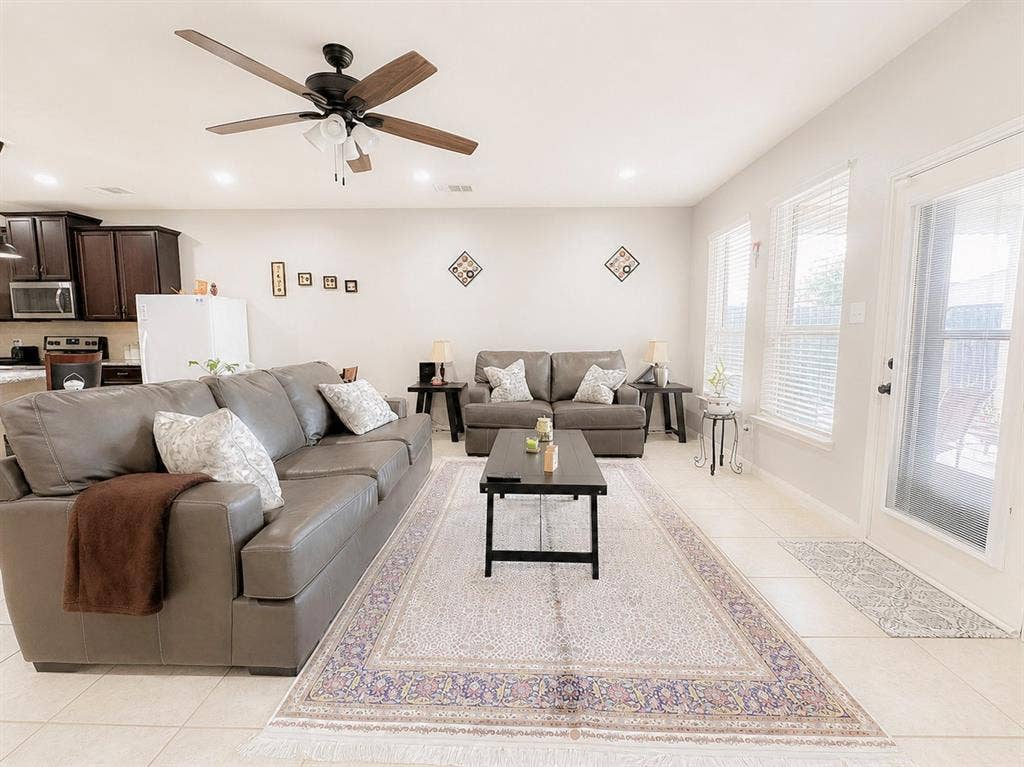 Bright living space featuring light-toned tile flooring, recessed lighting, and a ceiling fan with integrated lighting