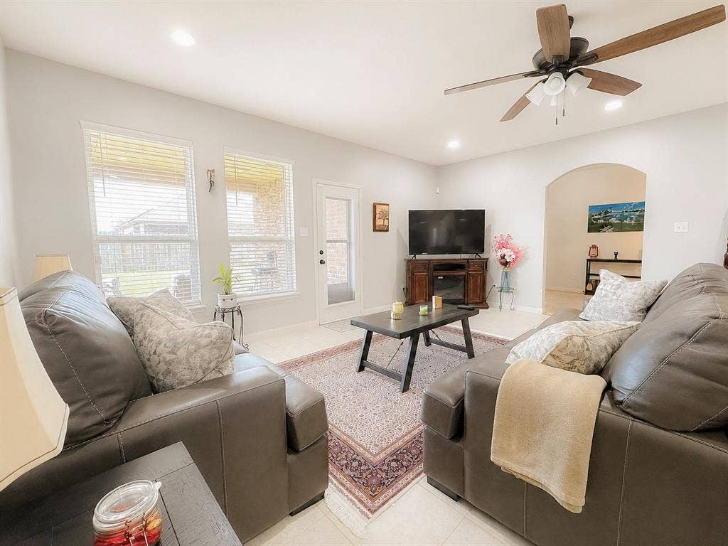 Recessed lighting throughout, arched doorway, ceiling fan with light fixture, tile flooring, and multiple windows
