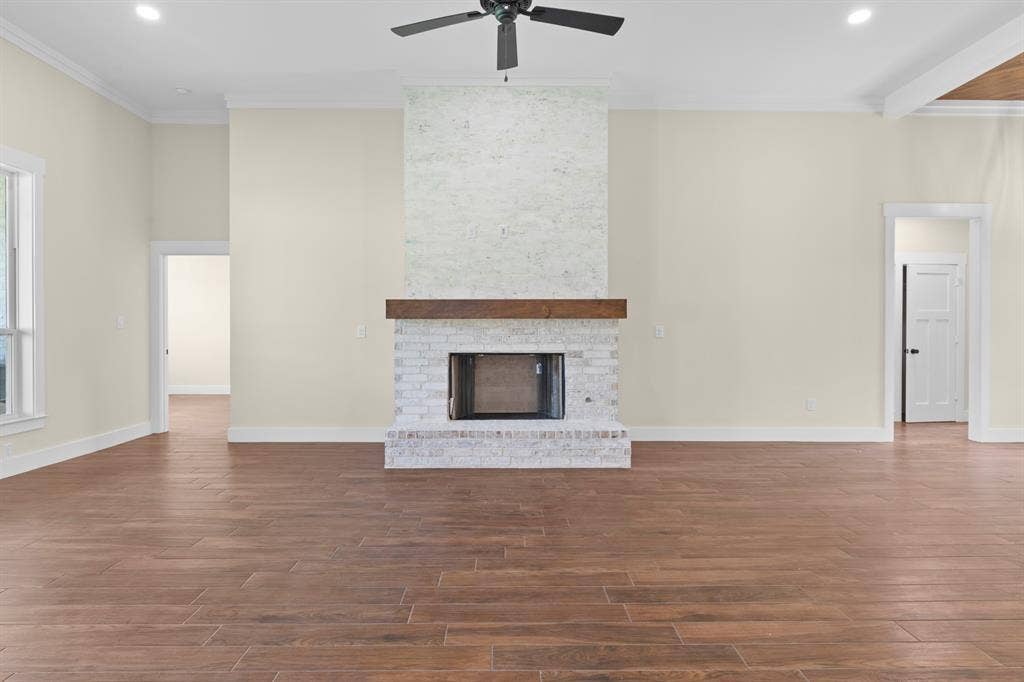 Spacious living area featuring wood-finish flooring, a white brick fireplace with a wood mantle, a ceiling fan, and recessed lighting