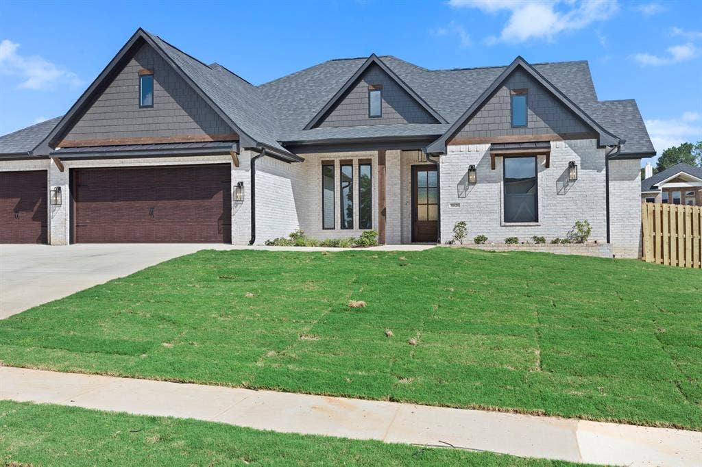Modern exterior featuring white brick, dark shingle roof, wood-look garage doors, and black-framed windows