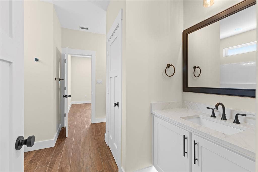 Vanity with white shaker-style cabinetry, quartz countertop, integrated sink, and matte black hardware