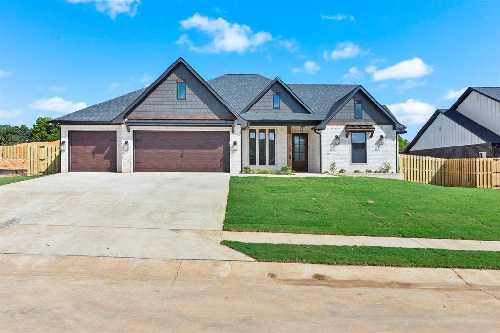 Modern farmhouse exterior with white brick and dark shingle siding, a three-car garage, and a newly installed lawn