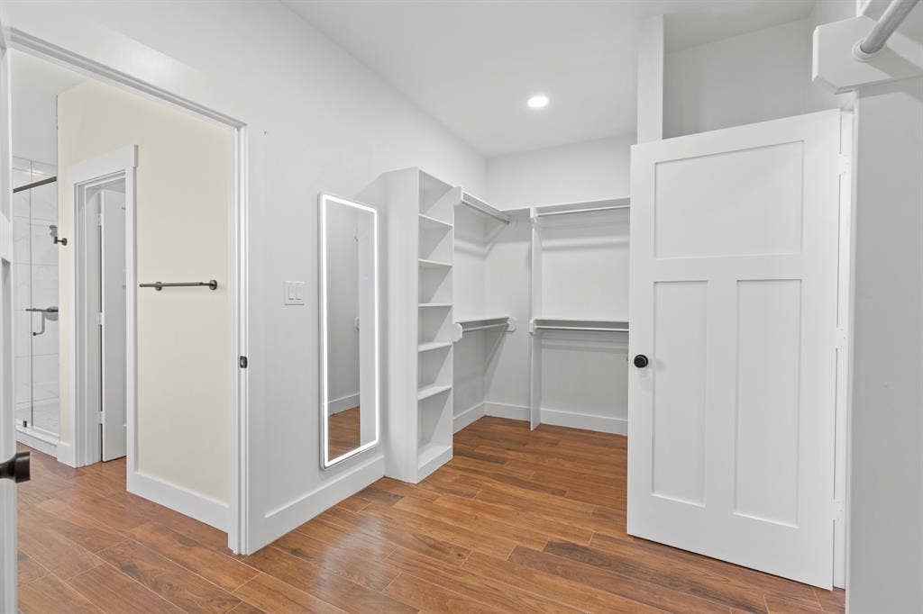 Walk-in closet with wood-finish flooring, built-in shelving, and integrated hanging rods