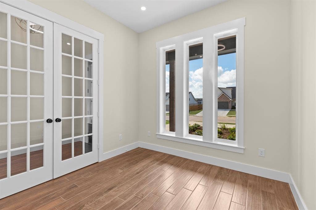 French doors with grid paneling, wood-finish flooring, recessed lighting, and three vertical windows with white trim