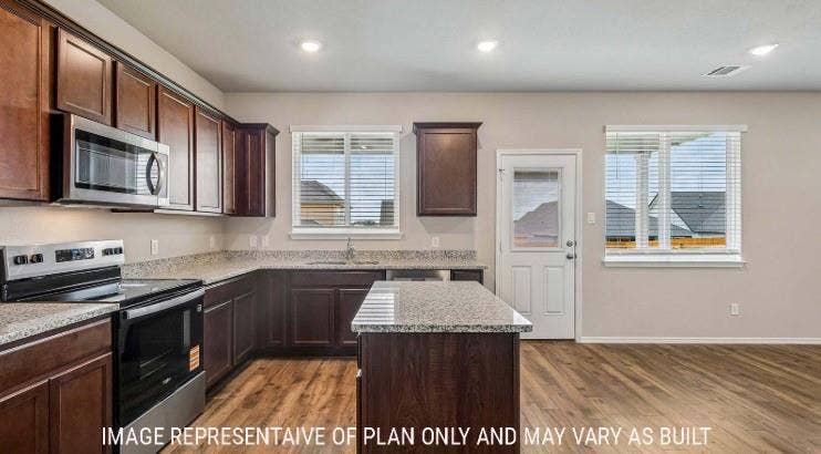 Wood-finish flooring, recessed lighting, and a kitchen island with stone countertops