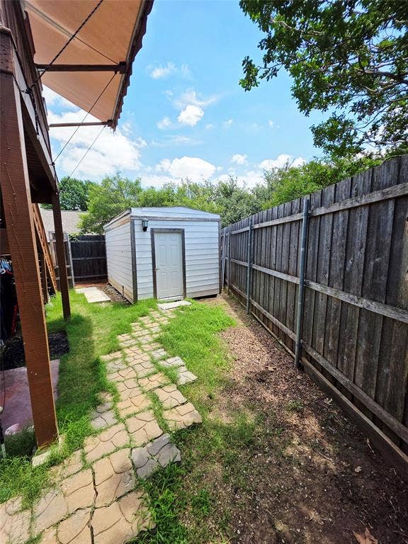 3009 Plumtree Lane, Plano, TX 75074 Wood privacy fencing with a storage shed, featuring a covered patio area and stone paver pathway