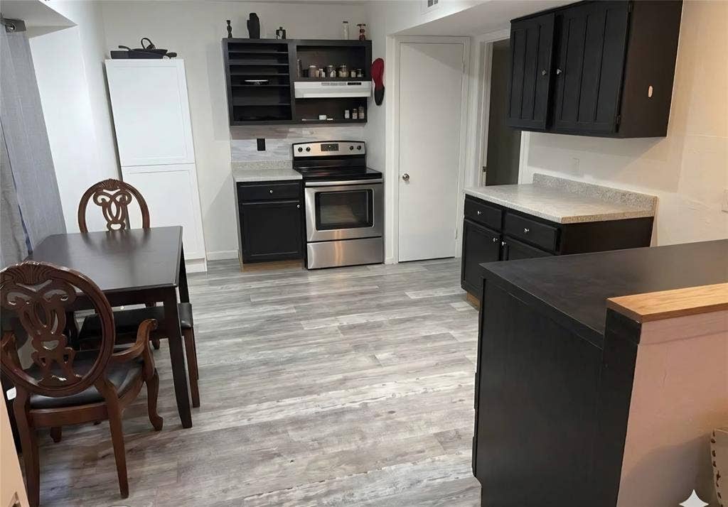 3009 Plumtree Lane, Plano, TX 75074 Wood-finish flooring, white countertops, built-in cabinetry, stainless steel range, and tile backsplash