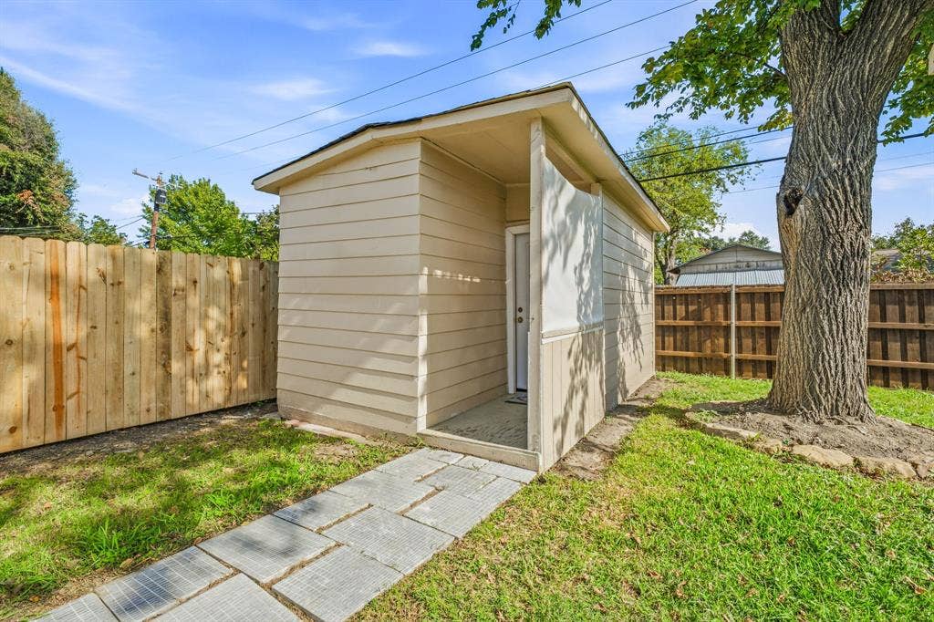 13706 Janwood Lane, Farmers Branch, TX 75234 Detached outbuilding featuring horizontal lap siding, a recessed entry, and a paver stone walkway set within a fenced yard