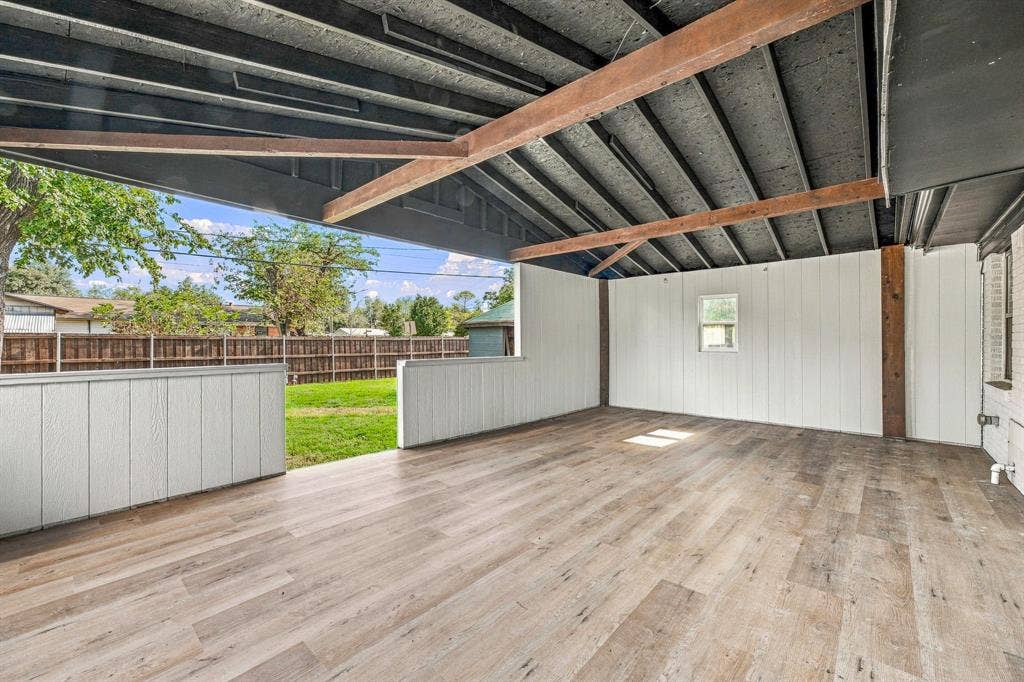 13706 Janwood Lane, Farmers Branch, TX 75234 Covered patio featuring wood-finish flooring, exposed ceiling beams, and vertical panel siding