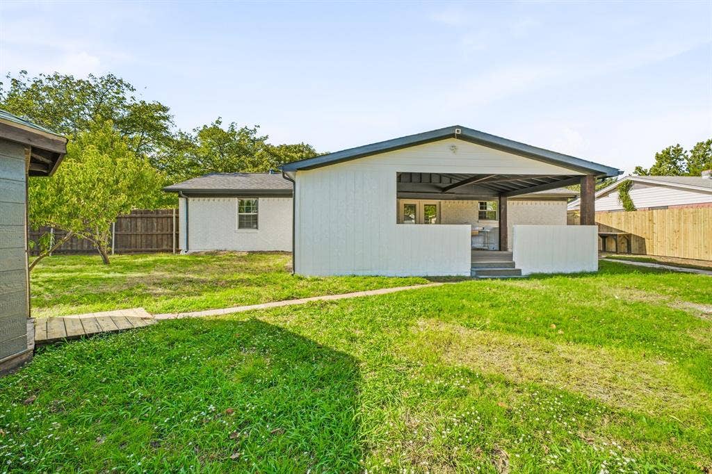 13706 Janwood Lane, Farmers Branch, TX 75234 Exterior rear elevation featuring a covered patio, painted siding, a fenced perimeter, and a grass lawn