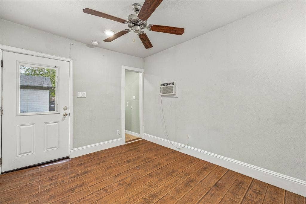 13706 Janwood Lane, Farmers Branch, TX 75234 Wood-finish flooring, ceiling fan with light fixture, exterior-access door with glass pane, and wall-mounted air conditioning unit