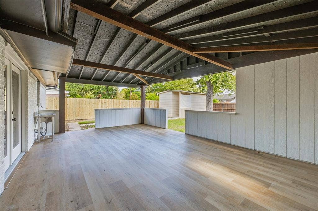 13706 Janwood Lane, Farmers Branch, TX 75234 Covered patio featuring wood-finish flooring, exposed structural beams, vertical plank siding, and a built-in utility sink