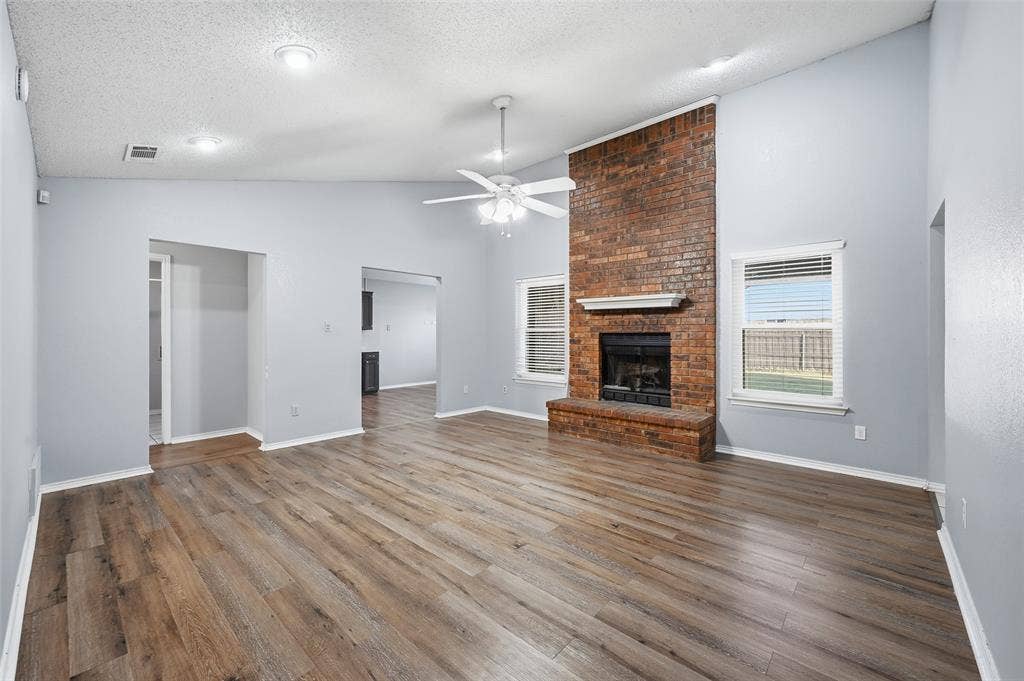 6421 Fairview Drive, Watauga, TX 76148 Vaulted ceiling, wood-finish flooring, brick fireplace with a white mantel, ceiling fan, and recessed lighting