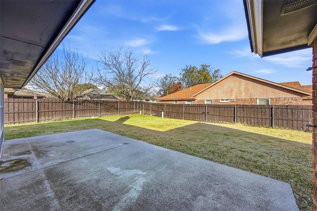 6421 Fairview Drive, Watauga, TX 76148 Expansive backyard featuring a concrete patio, a manicured lawn, and a wood privacy fence