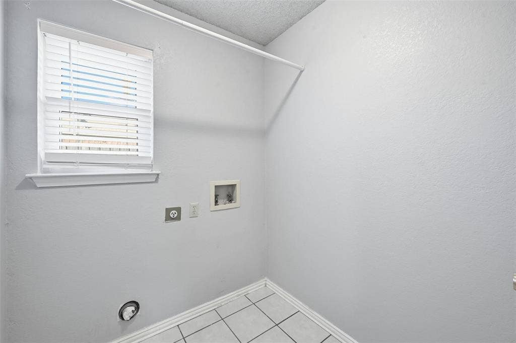 6421 Fairview Drive, Watauga, TX 76148 White wall paint, window with blinds, tiled flooring, wall-mounted laundry hookups, and a clothes hanging rod