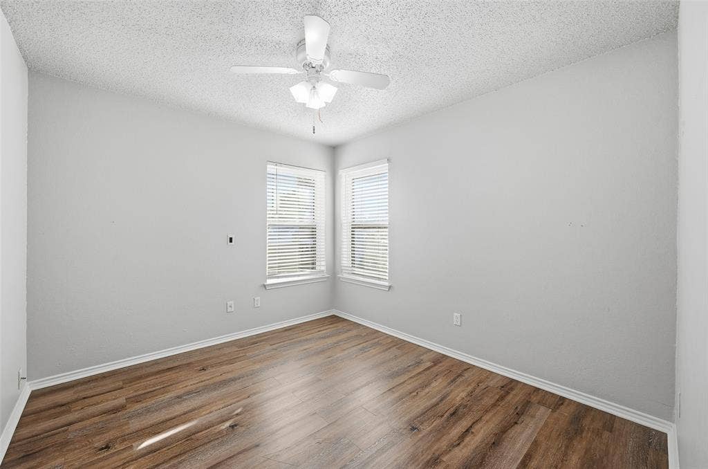 6421 Fairview Drive, Watauga, TX 76148 Wood-finish flooring, corner windows with blinds, and a ceiling fan with integrated lighting
