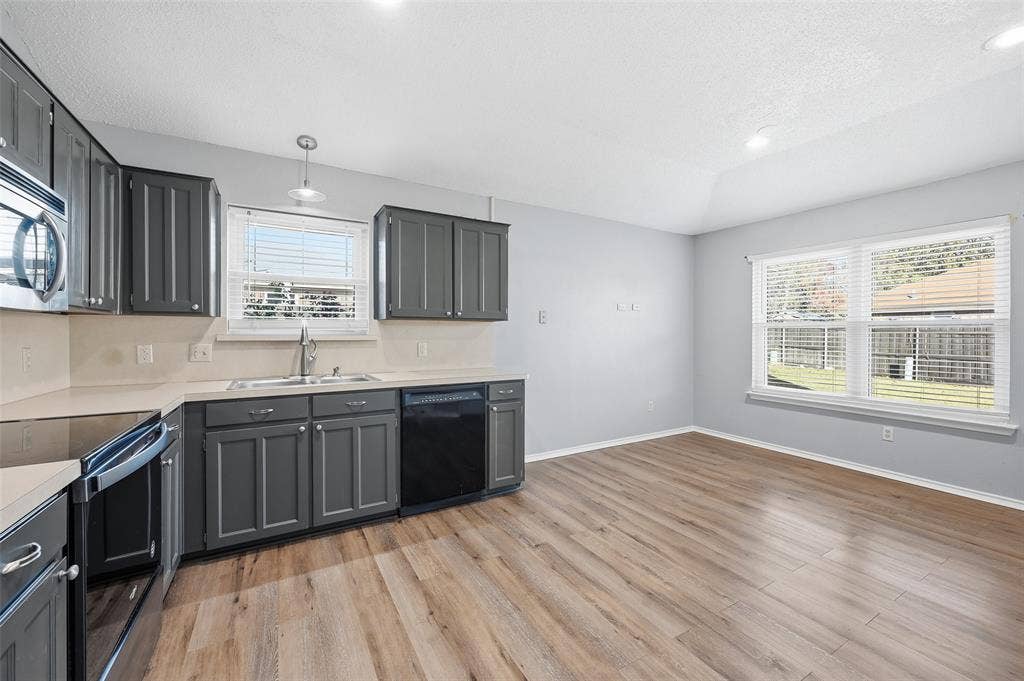 6421 Fairview Drive, Watauga, TX 76148 Kitchen featuring grey cabinetry, stainless steel appliances, light countertops, and wood-finish flooring