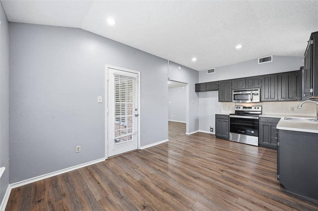 6421 Fairview Drive, Watauga, TX 76148 Wood-finish flooring, recessed lighting, and a kitchen featuring dark cabinetry with stainless steel appliances and light countertops
