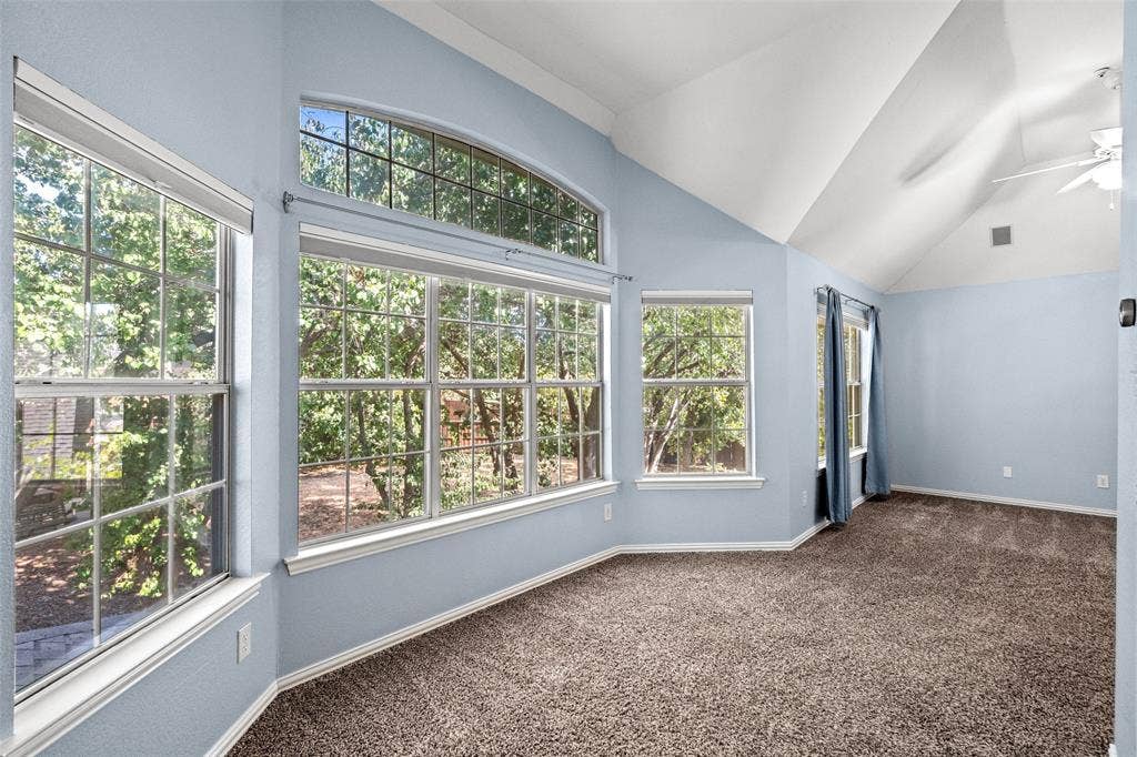 14592 Aspen Court, Addison, TX 75001 Vaulted ceiling with a ceiling fan, multiple windows with grid patterns, an arched transom window, and textured wall finish