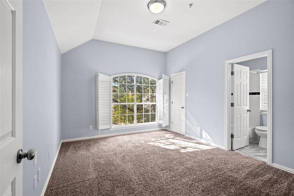 14592 Aspen Court, Addison, TX 75001 Vaulted ceiling, arched window with plantation shutters, plush carpeting, and an attached bathroom with tiled flooring