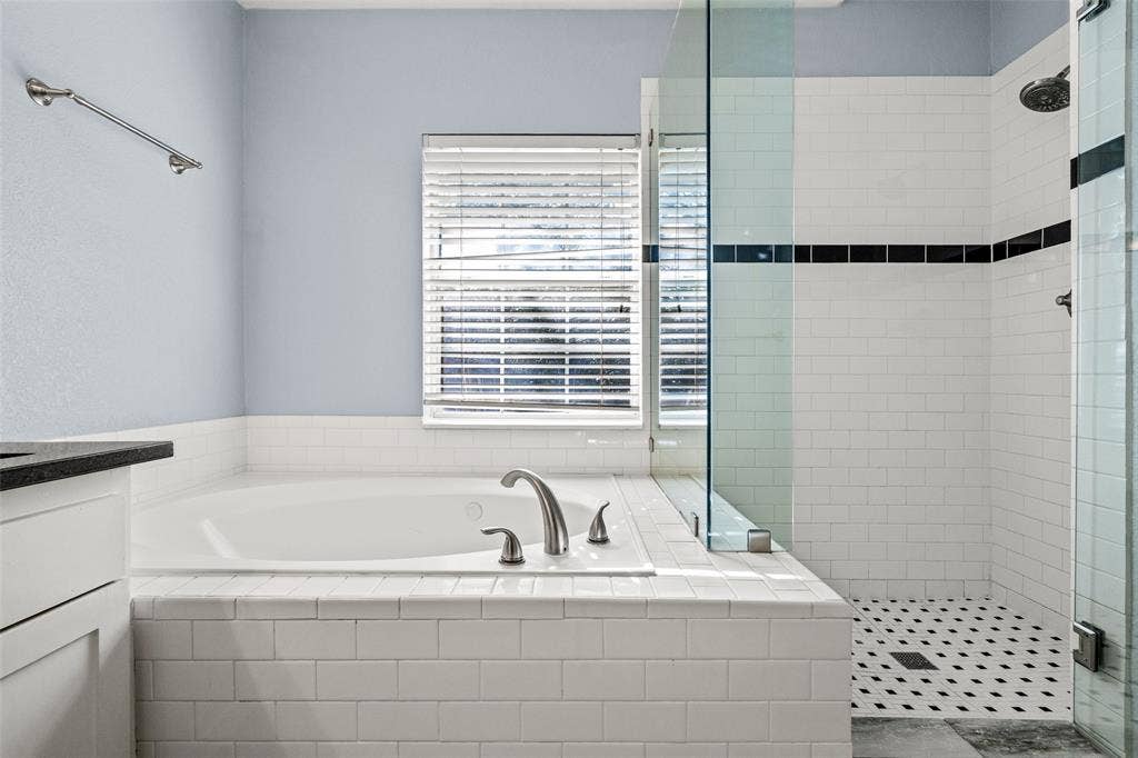 14592 Aspen Court, Addison, TX 75001 Deep soaking tub with brushed nickel fixtures, white subway tile surround, and a clear glass shower enclosure