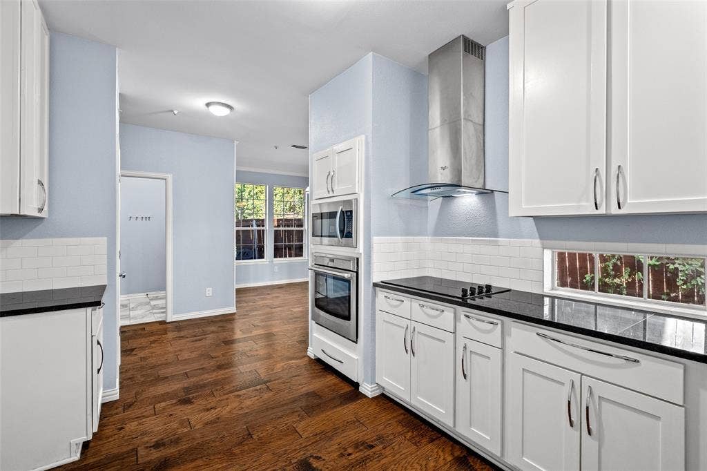 14592 Aspen Court, Addison, TX 75001 Kitchen with wood-finish flooring, white cabinetry, integrated stainless steel appliances, dark countertops, and white subway tile backsplash