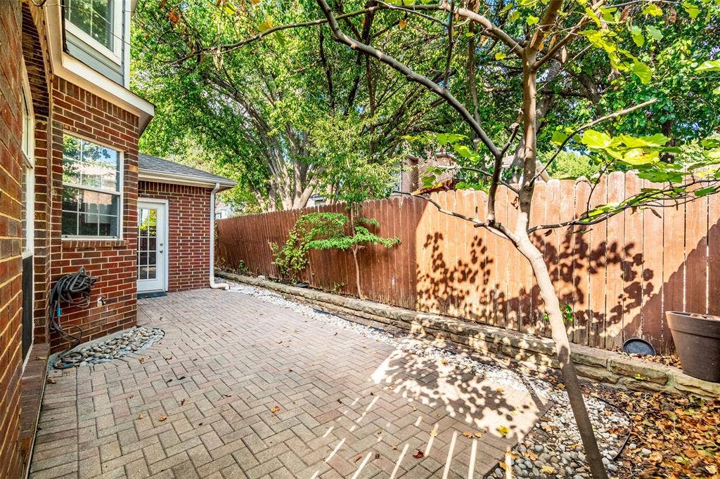 14592 Aspen Court, Addison, TX 75001 Brick exterior construction with white window frames, a white multi-pane glass door, and a paver patio