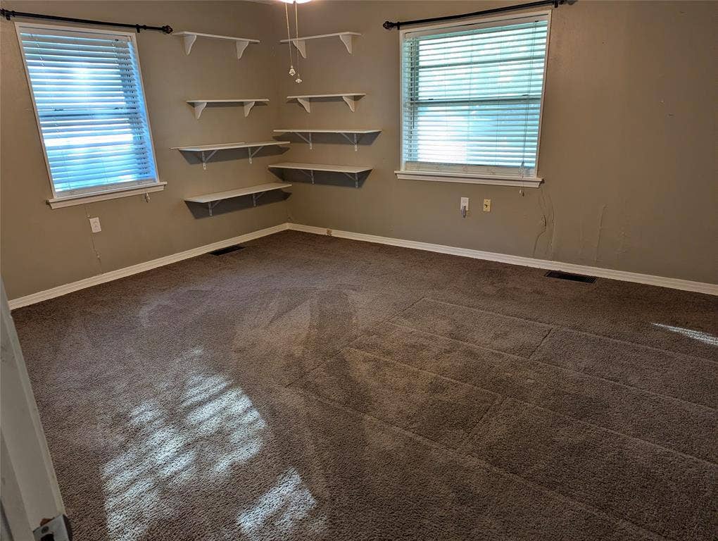 111 Murchison Street, Farmersville, TX 75442 Bedroom #3 – View 1: Spacious secondary bedroom located in the southeast corner of the home, featuring two windows overlooking the front yard, carpeted flooring, and built-in corner shelving.