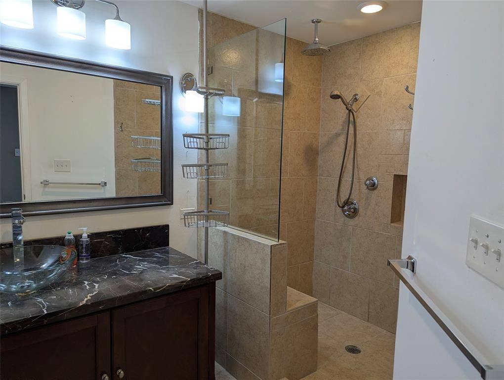 111 Murchison Street, Farmersville, TX 75442 View 1: Updated ensuite bathroom featuring a dark vanity, granite-look countertop, framed mirror, and spacious tiled walk-in shower.