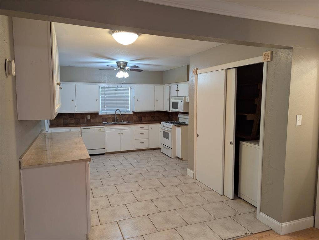 111 Murchison Street, Farmersville, TX 75442 The kitchen offers tile flooring, white cabinetry, and a functional layout with potential for future updates.