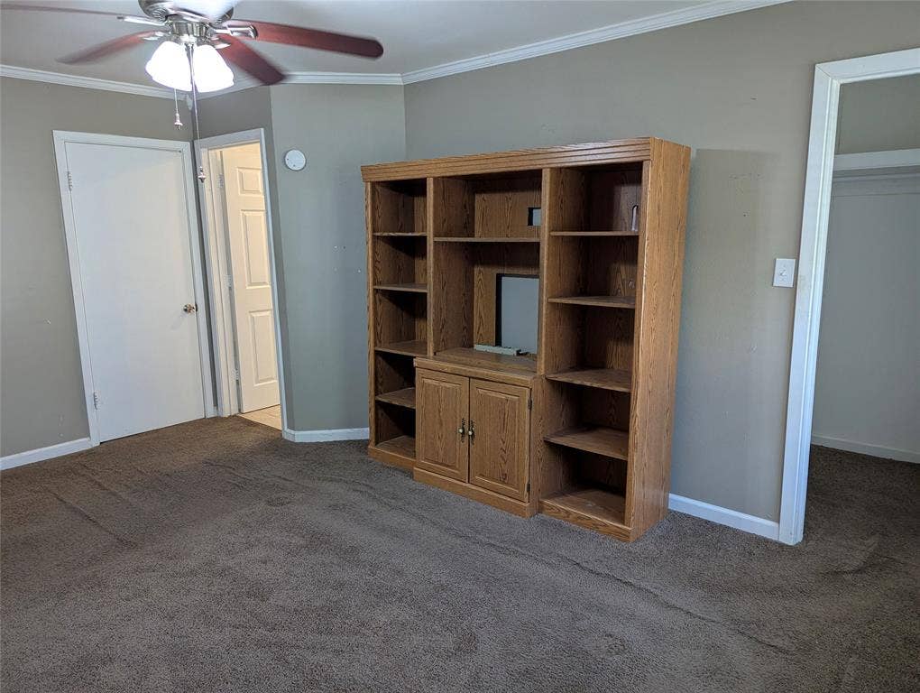111 Murchison Street, Farmersville, TX 75442 View 3: Spacious primary bedroom featuring carpeted flooring, a ceiling fan, and built-in shelving for display or storage.