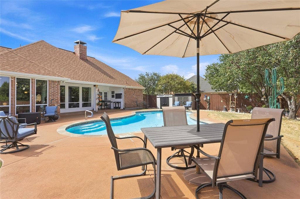 1926 Vintage Drive, Corinth, TX 76210 Backyard oasis featuring a freeform swimming pool, extensive patio, and brick exterior