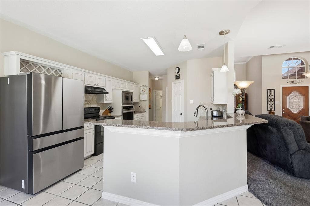 1926 Vintage Drive, Corinth, TX 76210 Kitchen featuring white cabinetry, built-in wine storage, stainless steel appliances, and a peninsula with a stone countertop