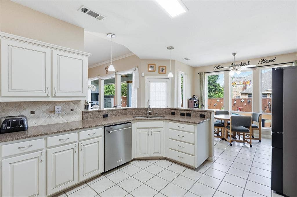 1926 Vintage Drive, Corinth, TX 76210 White cabinetry with brushed nickel pulls, granite-finish countertops, and a mosaic tile backsplash