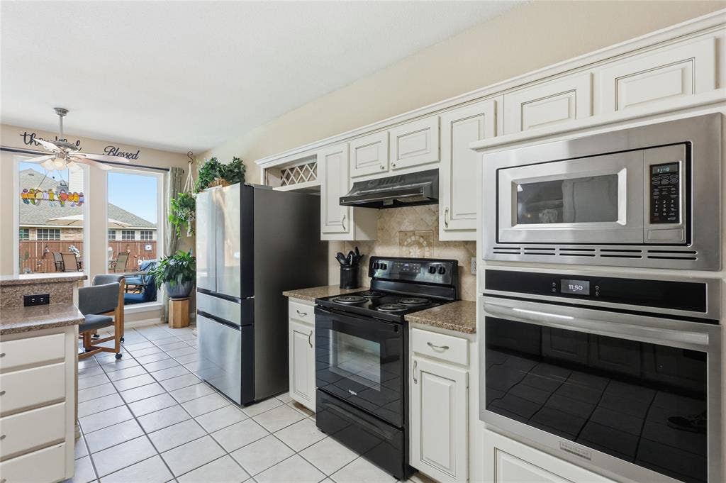 1926 Vintage Drive, Corinth, TX 76210 Kitchen with white tile flooring, white cabinetry, integrated stainless steel microwave, black electric range, and light-colored countertops
