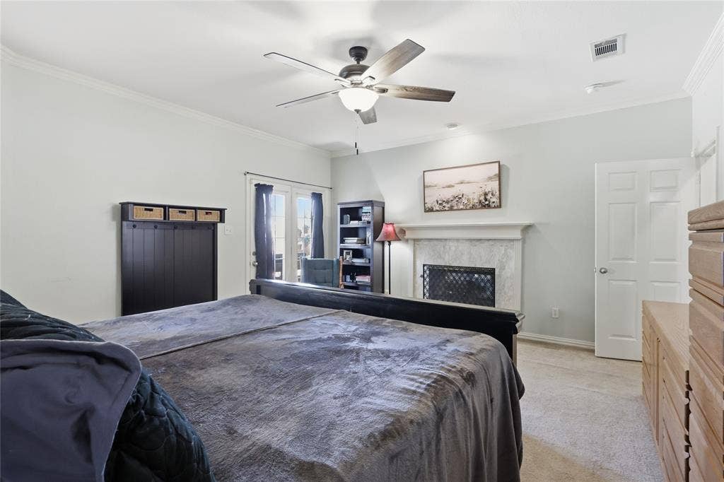 1926 Vintage Drive, Corinth, TX 76210 Carpeted room featuring a ceiling fan with light, a fireplace with a stone surround, and crown molding