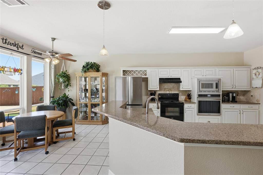 1926 Vintage Drive, Corinth, TX 76210 Kitchen featuring white cabinetry, stone-finish countertops, stainless steel appliances, and tile flooring