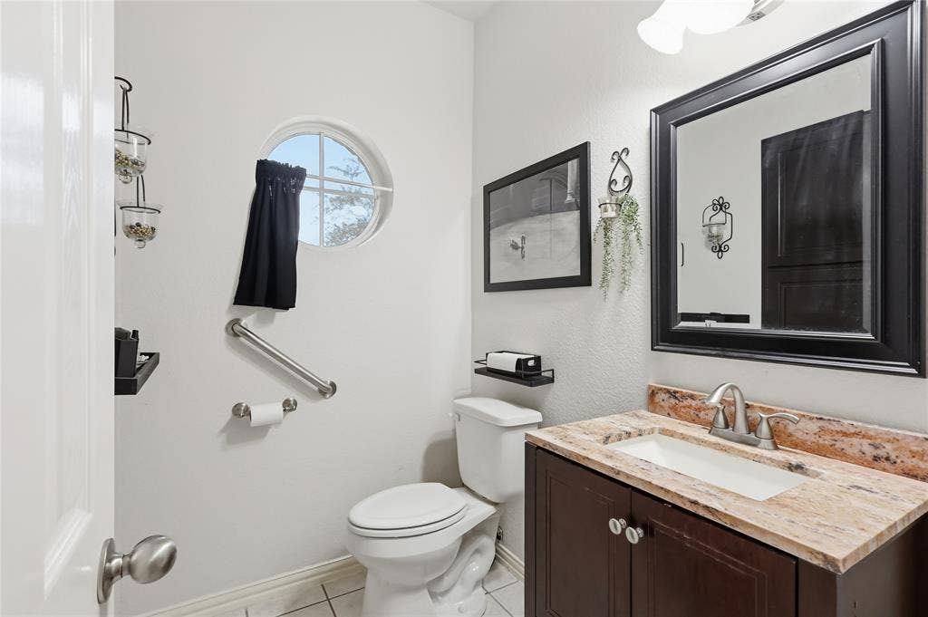 1926 Vintage Drive, Corinth, TX 76210 Round window, vanity with stone-finish countertop, integrated sink, large framed mirror, and tile flooring