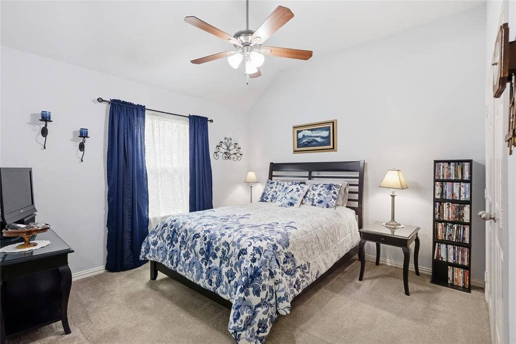 1926 Vintage Drive, Corinth, TX 76210 Vaulted ceiling with a ceiling fan, window with curtain rods, sconce lighting, and carpet flooring