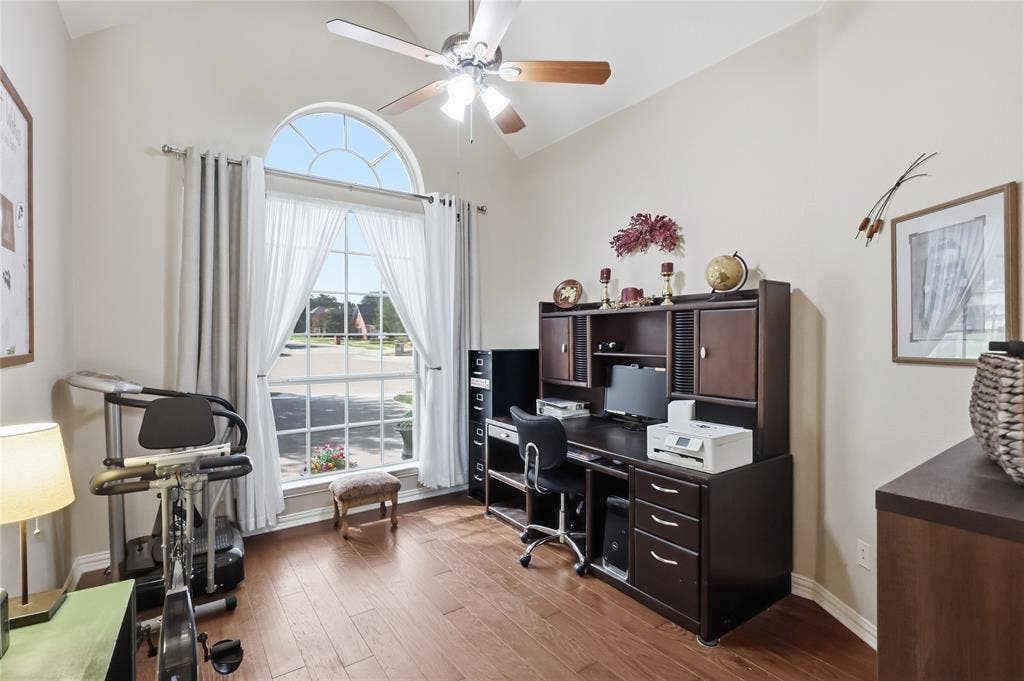 1926 Vintage Drive, Corinth, TX 76210 Arched transom window above a large picture window, vaulted ceiling, wood-finish flooring, and a ceiling fan with light fixture