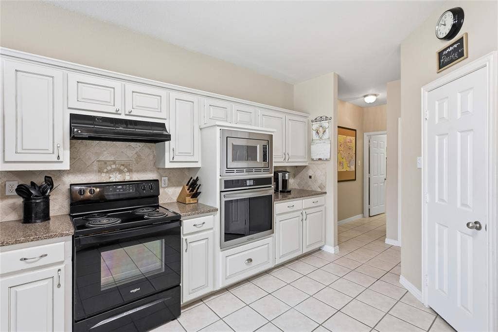 1926 Vintage Drive, Corinth, TX 76210 White cabinetry, tile flooring, granite-style countertops, stainless steel microwave, and built-in oven