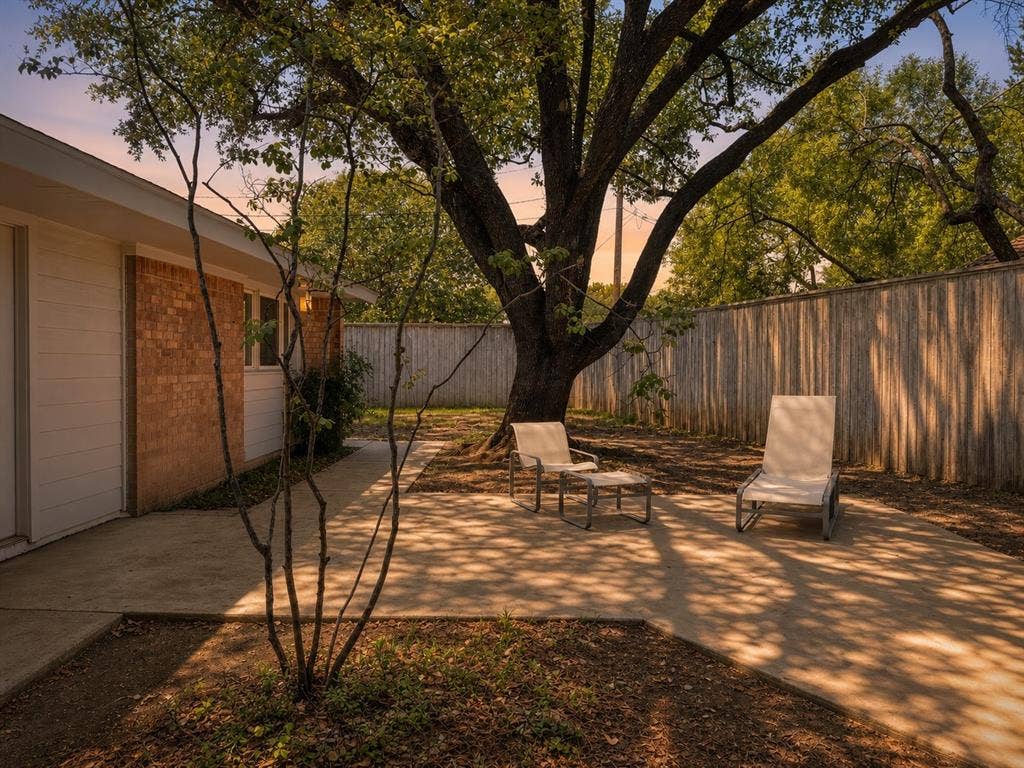 3401 Hanover Lane, Irving, TX 75062 Expansive outdoor patio with mature trees, a wood privacy fence, and brick and siding exterior