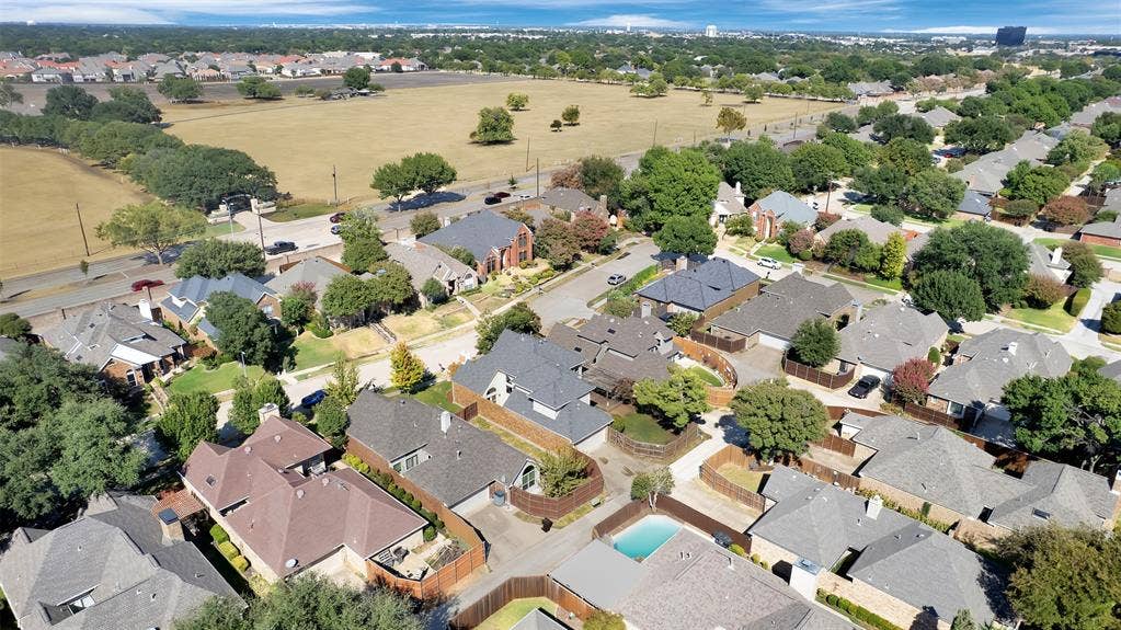 1920 Keystone Drive, Plano, TX 75075 Aerial perspective showcasing a residential area with mature trees, varied rooflines, and a nearby open field