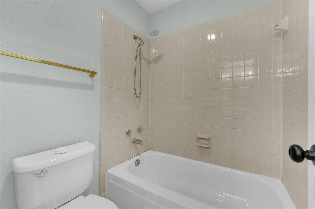 1920 Keystone Drive, Plano, TX 75075 White porcelain bathtub with a shower head and tile surround