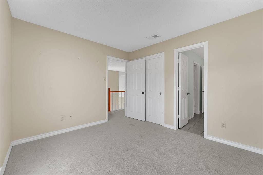 1920 Keystone Drive, Plano, TX 75075 Neutral tone wall paint, light-colored carpeting, white trim, and white bi-fold closet doors