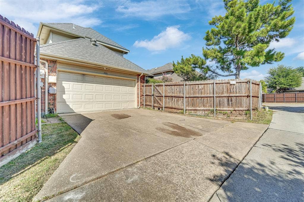1920 Keystone Drive, Plano, TX 75075 Attached two-car garage with a concrete driveway, complemented by a wood fence and mature trees