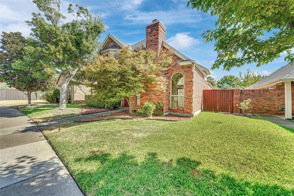 1920 Keystone Drive, Plano, TX 75075 Brick exterior with an arched window, a prominent chimney, and mature landscaping