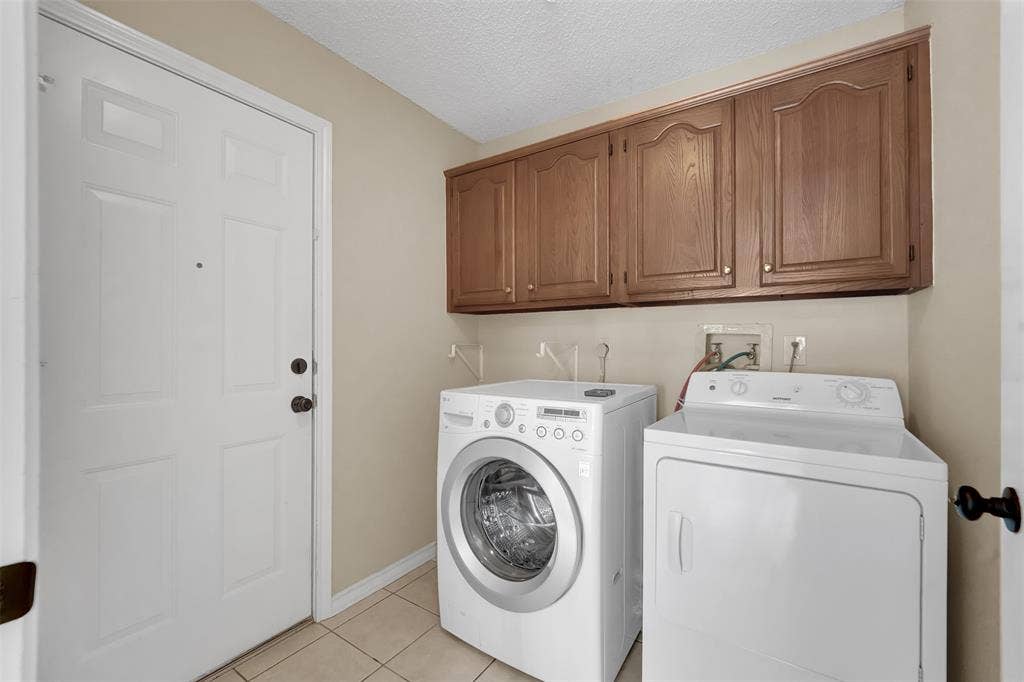 1920 Keystone Drive, Plano, TX 75075 Laundry area with upper wood cabinetry and tile flooring